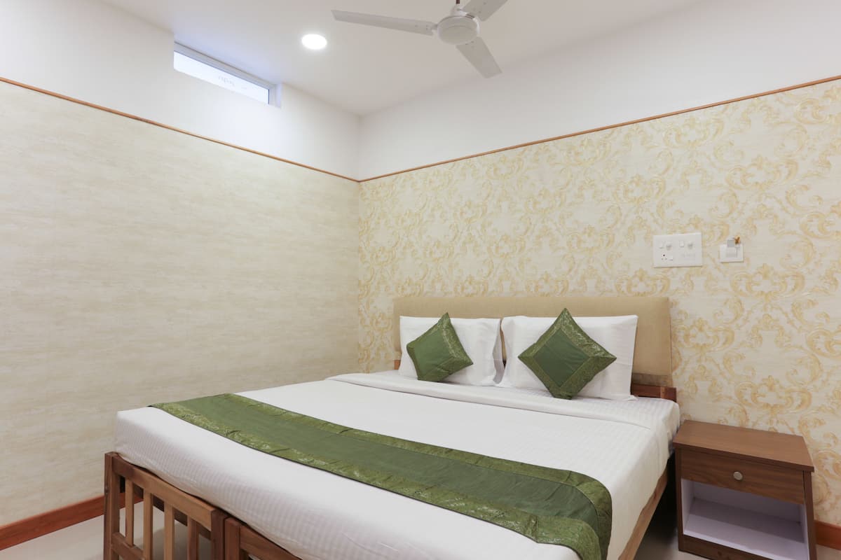 Quarto com cama, mesa de cabeceira, ventoinha no teto e janela.