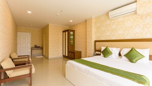 Habitación de hotel con cama, armario de madera, escritorio y silla, y unidad de aire acondicionado.