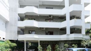 Un edificio de varios pisos con balcones, una entrada cubierta y fachada de ladrillo.
