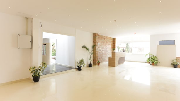 Un vestíbulo amplio y luminoso con un diseño moderno, que cuenta con una pared de ladrillo decorativa, plantas en macetas y una recepción.