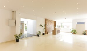 A spacious, well-lit lobby with a modern design, featuring a brick accent wall, potted plants, and a reception desk. - Treebo Trend Heaven Gardens (Kanayannur)