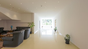 Amplia sala de estar muy iluminada, con un diseño moderno, que incluye un sofá de cuero, una mesa de centro y varias plantas en macetas.