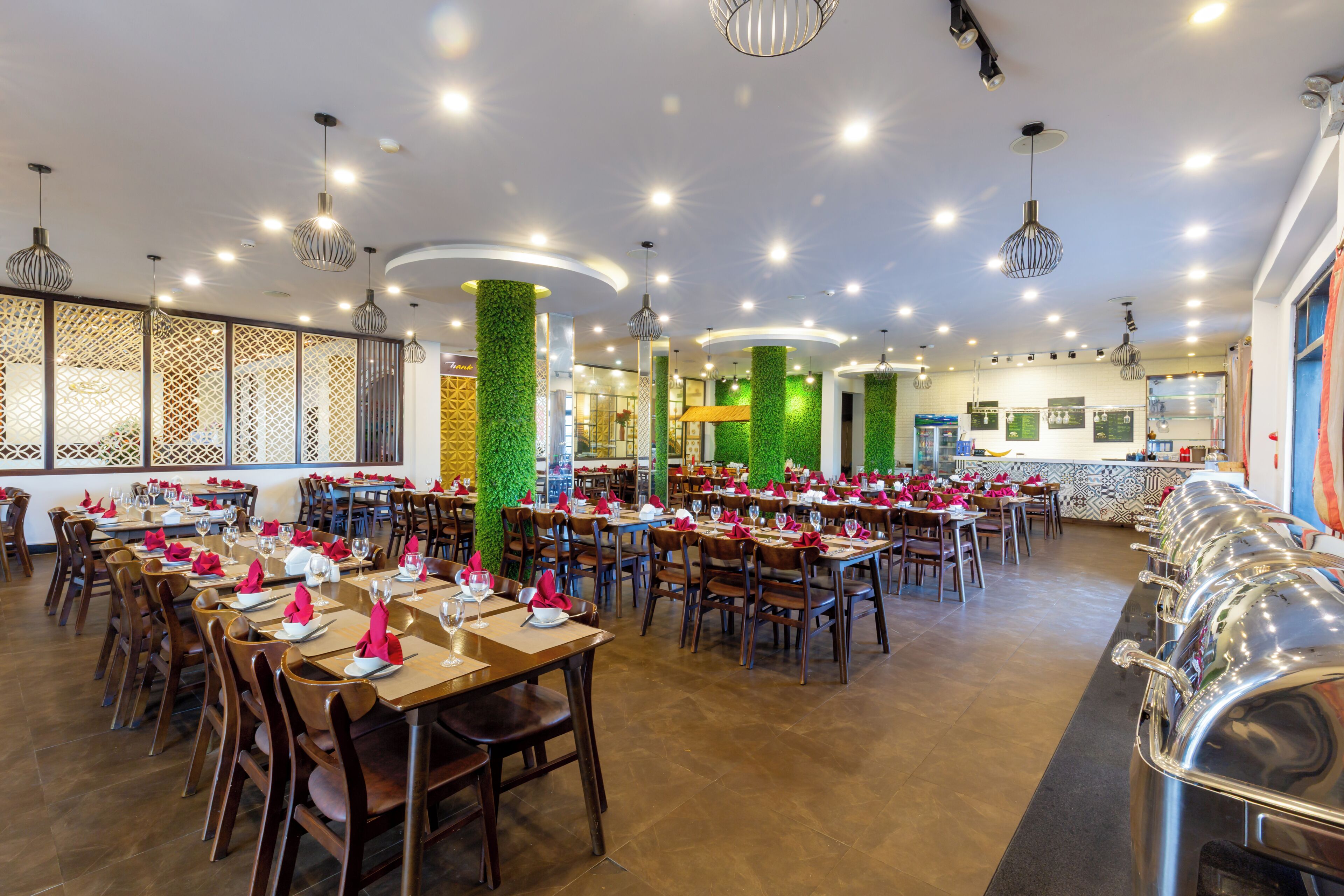 A restaurant with multiple dining tables, chairs, and a variety of ceiling lights.