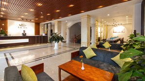 En modern hotellobby med en receptionsdisk, en sittgrupp och dekorativa växter.
