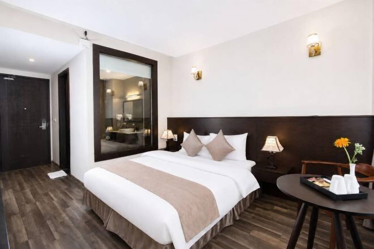 A hotel room with a large bed, bedside tables, a desk, and a chair.