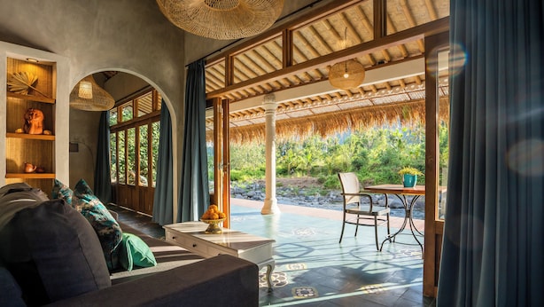 Una habitación con sofá, una mesa y vistas a zonas verdes.