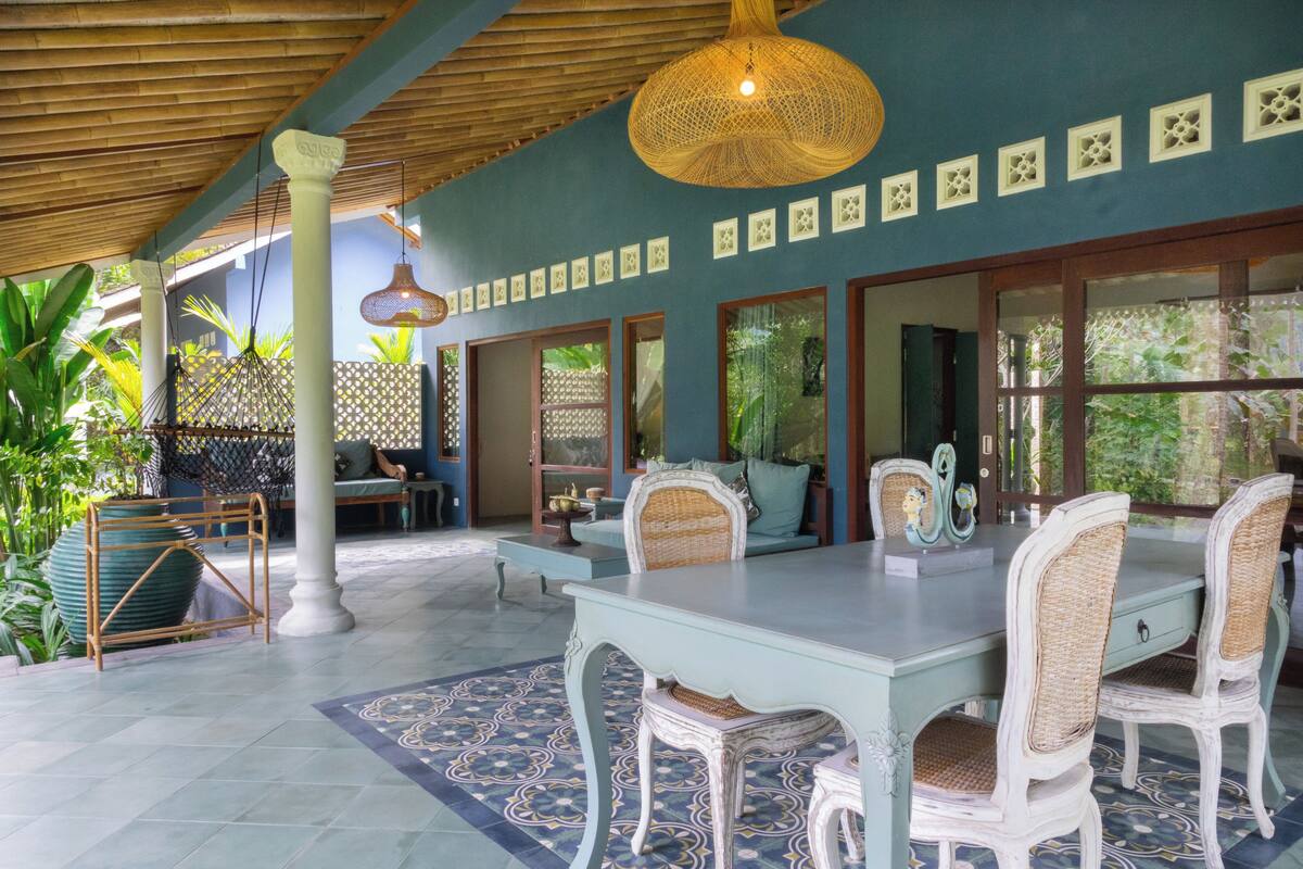 Un amplio patio con una mesa y sillas, rodeado de grandes ventanales y un techo decorativo.