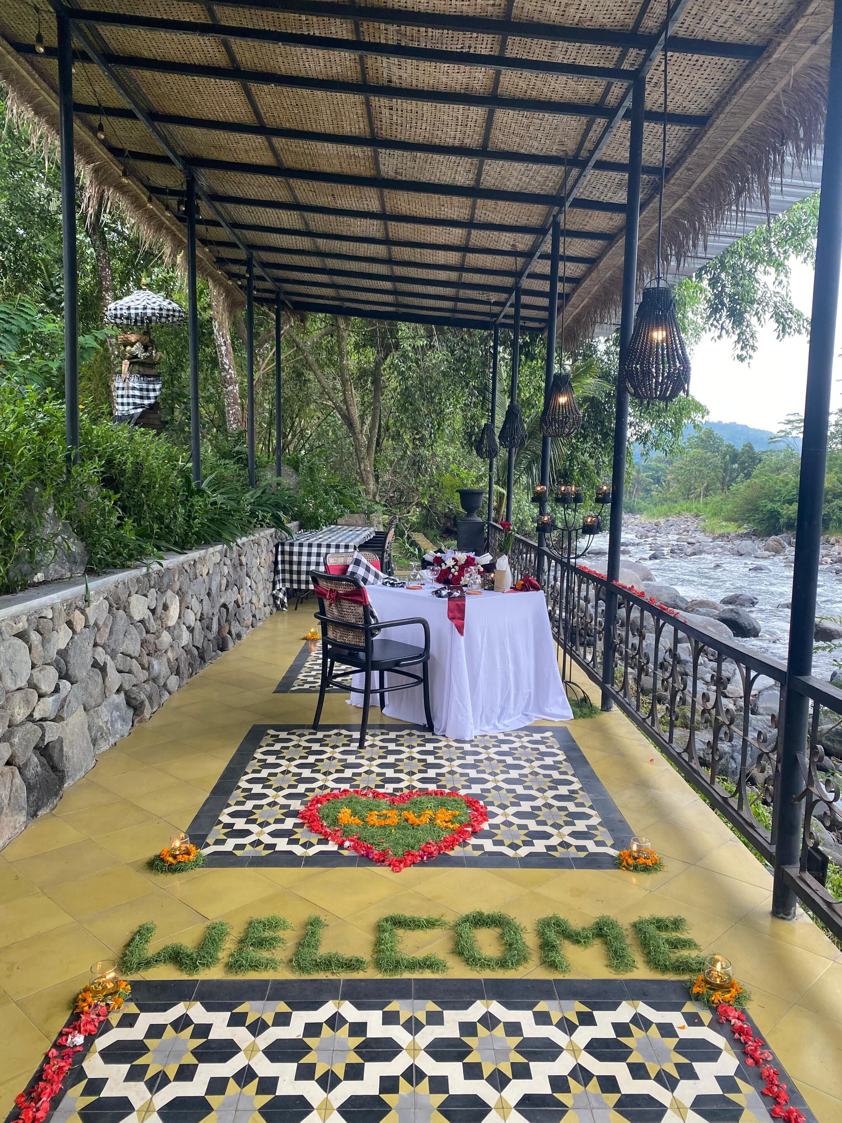 Un espacio exterior para comer con una mesa dispuesta para dos, un muro de piedra y un felpudo.