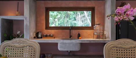 Una cocina con ventana, un lavamanos y una encimera con varios objetos.
