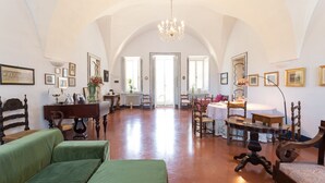 A spacious room with high ceilings, a chandelier, and a view through an arched doorway. - Villa Spada Donadeo (Lequile)