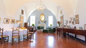 A spacious room with a high arched ceiling, a chandelier, a fireplace, and a long wooden table with chairs. - Villa Spada Donadeo (Lequile)