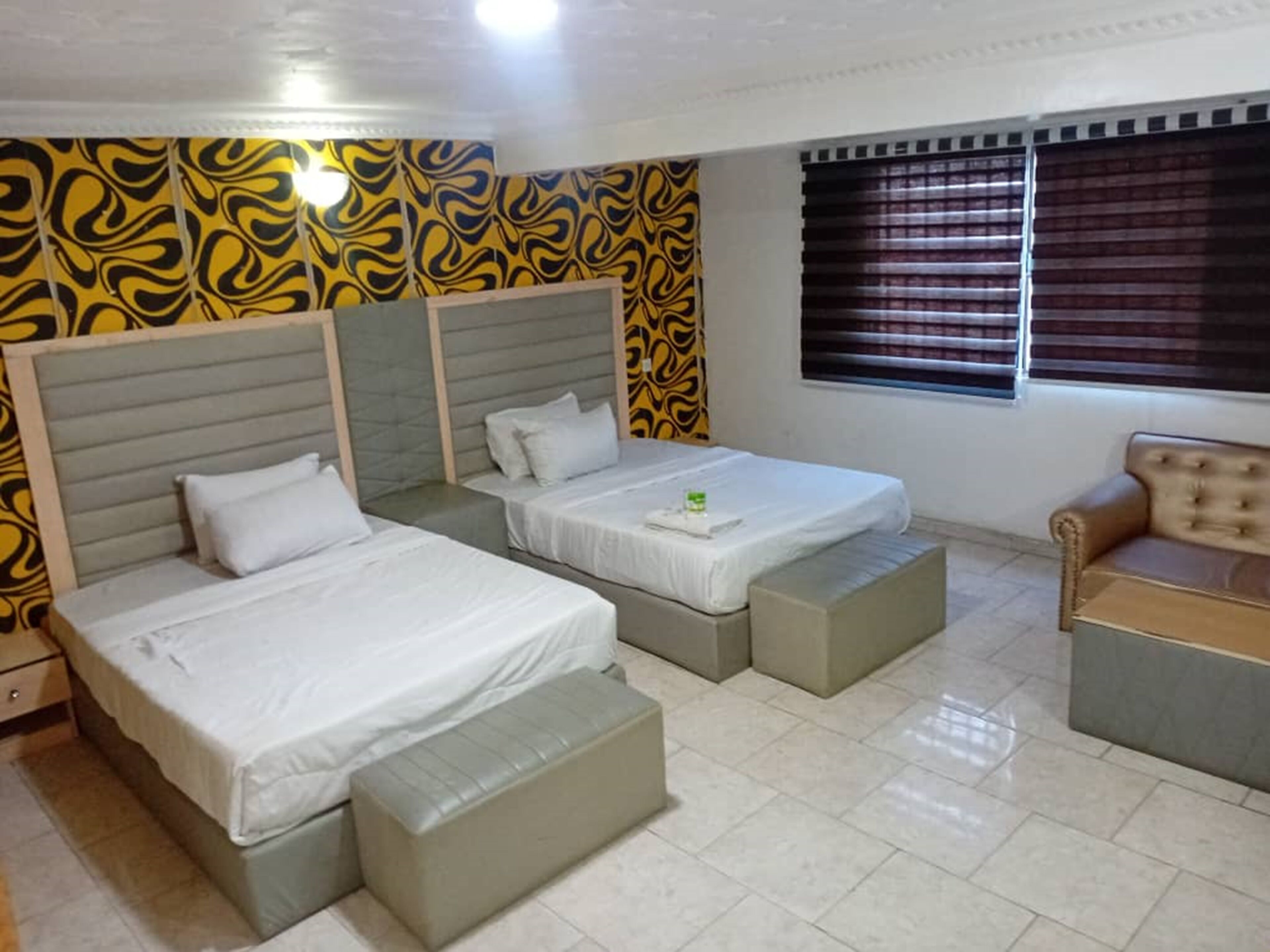 Una habitación de hotel con dos camas, un sofá y una ventana con persianas.