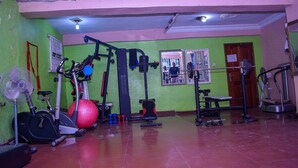 A gym with exercise equipment, a fan, and a door. - Duban International Hotels (Lagos)