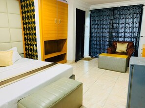 Habitación de hotel con cama, sofá, armario de madera y cortina estampada.