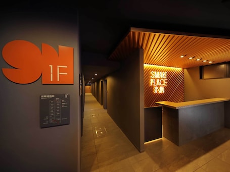 A hotel reception area with a modern design, including a reception desk and a wall-mounted emergency route sign.