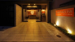 La entrada de un hotel con un letrero que dice "SMART PLACE INN" y un camino empedrado que lleva a la entrada.