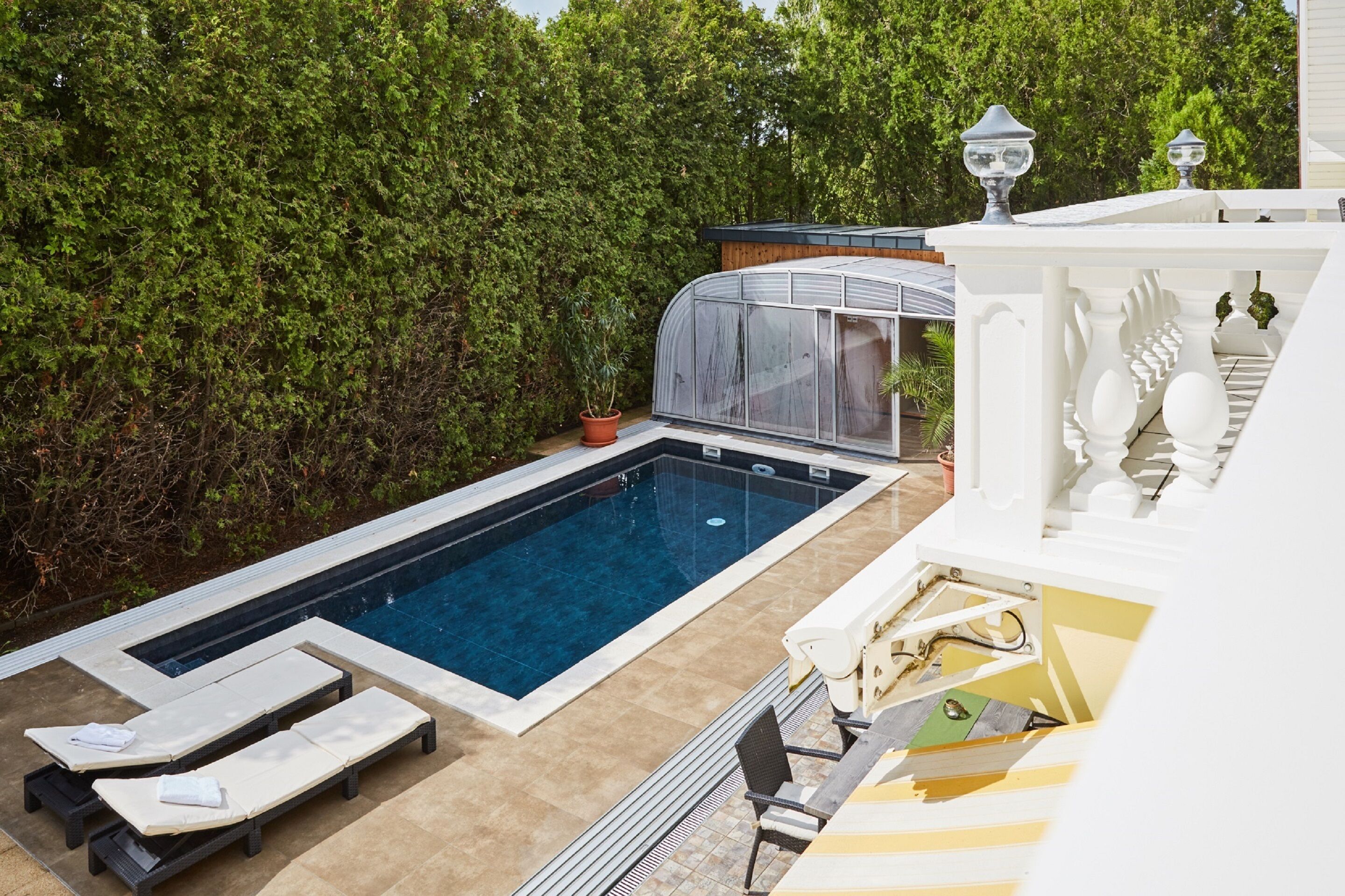 Una piscina con sillones de descanso y una estructura tipo invernadero.
