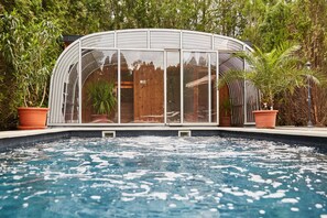 Relax in a serene pool area surrounded by lush greenery and a curved roof structure.