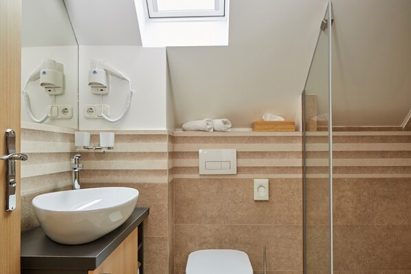 Un baño moderno con un lavabo grande blanco, cabina de ducha de vidrio y un perchero para toallas.