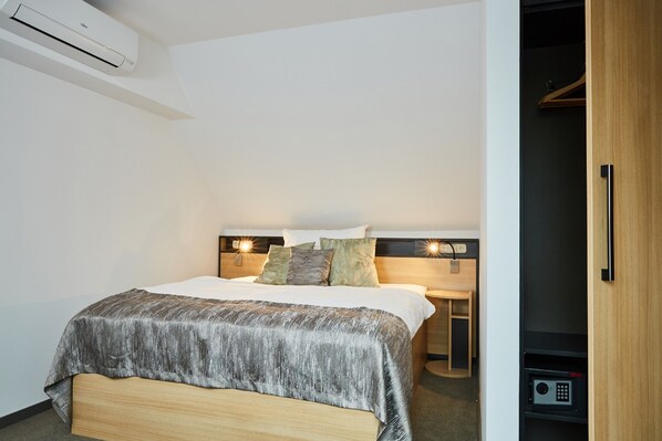 A modern hotel room with a bed, bedside tables, an air conditioning unit, and a wardrobe. - Gold Haus Panzió (Balatonfured)