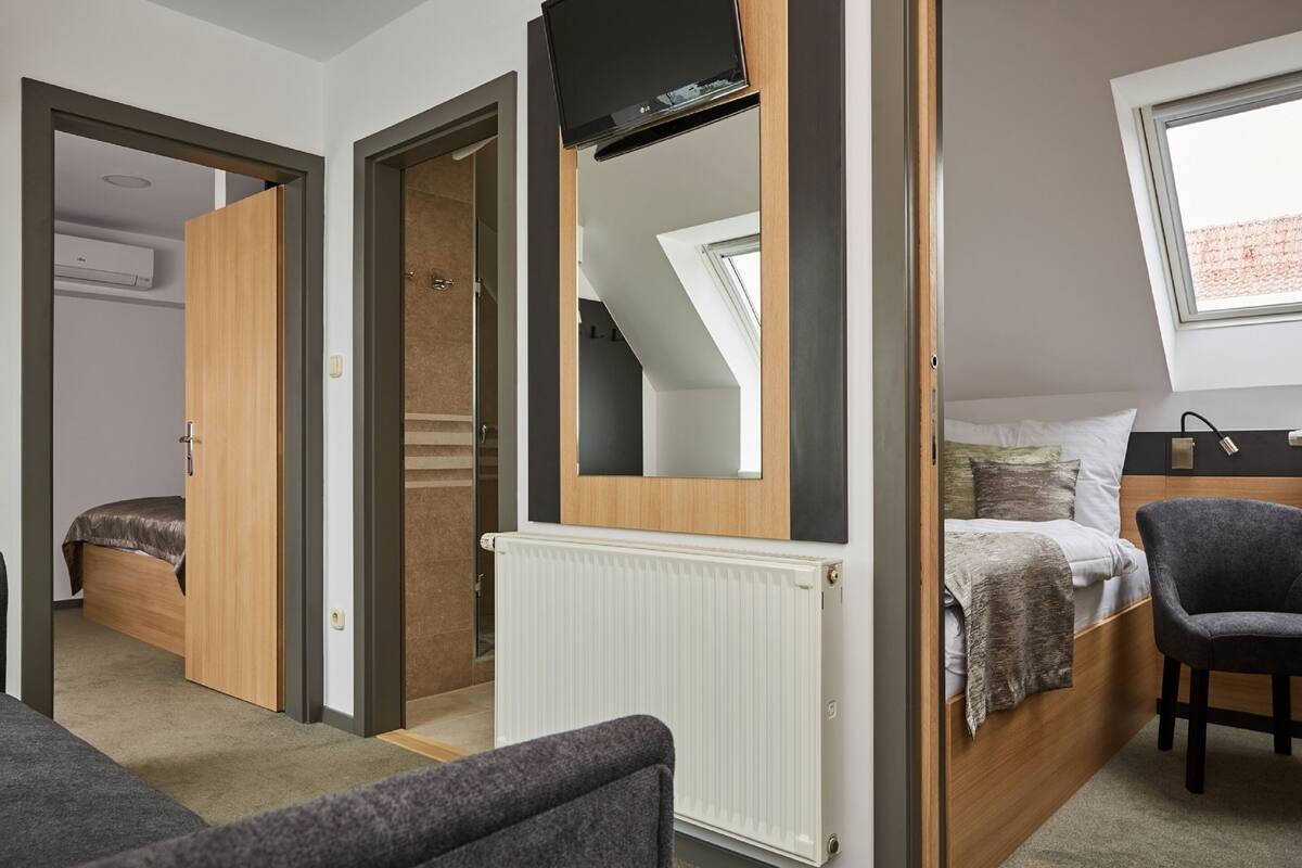 A bedroom with a bed, a chair, a radiator, and a TV.