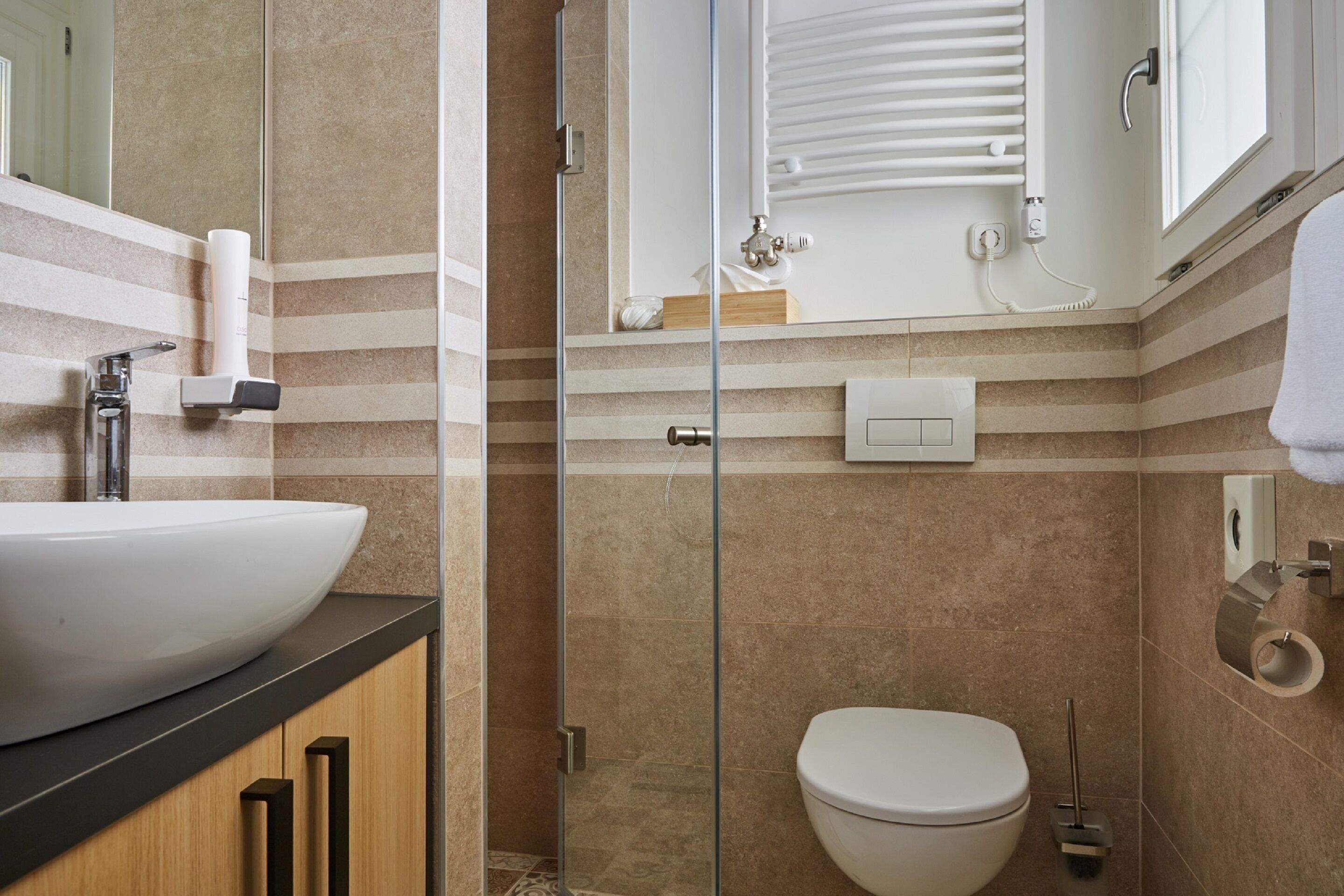 A modern bathroom with a large white sink, a glass shower enclosure, and a toilet.