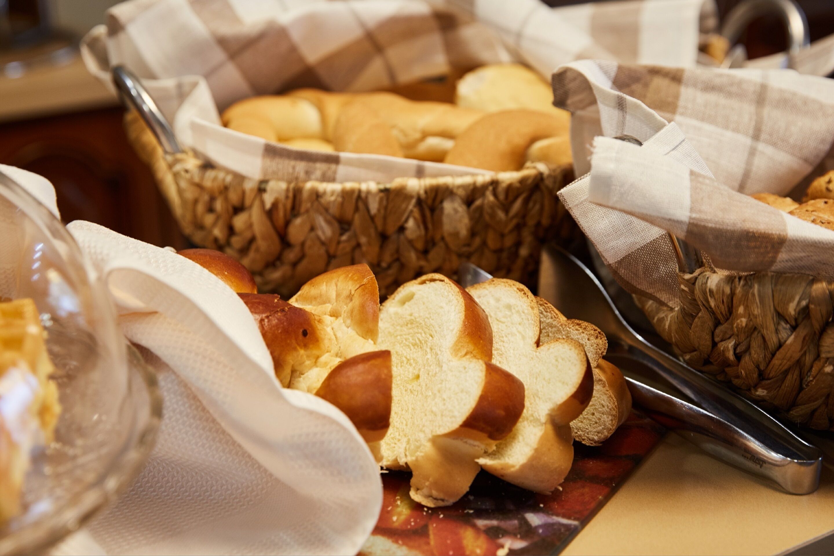 A basket of bread rolls and a glass of juice on a table.