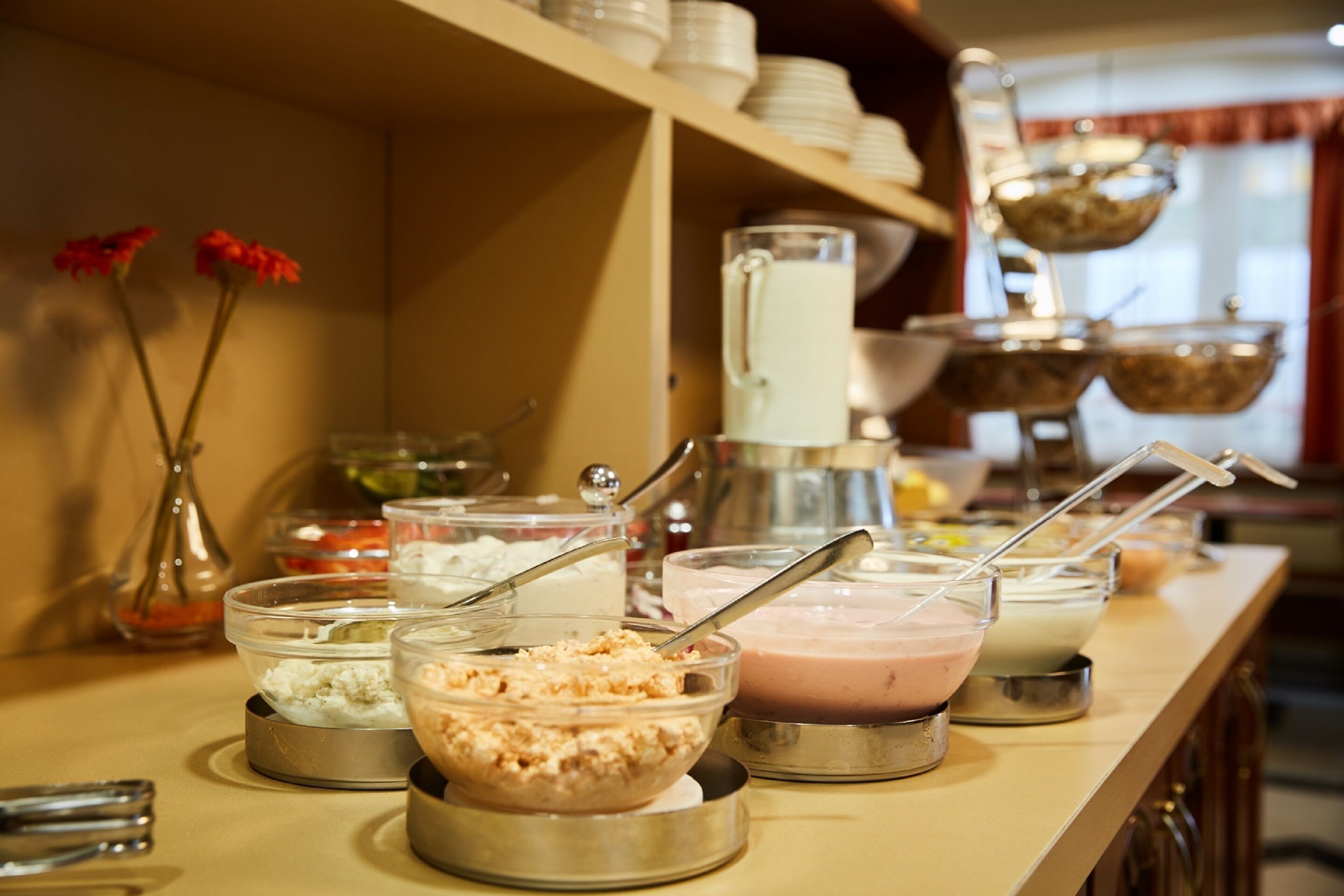 Un bufé con distintos alimentos y un dispensador de leche.