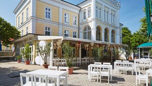 Un bâtiment historique doté d’un café avec une terrasse offrant des places assises en plein air et agrémentée de plantes en pot.