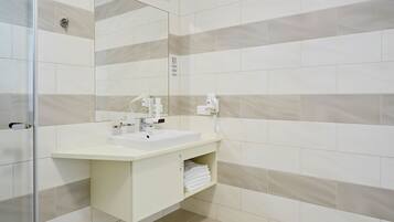 Un bany modern amb un lavabo blanc, un mirall i un suport per a tovalloles.