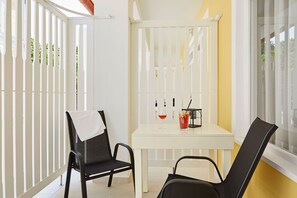 A small, enclosed outdoor seating area with a white table and two black chairs. - Astoria Hotel (Balatonfured)
