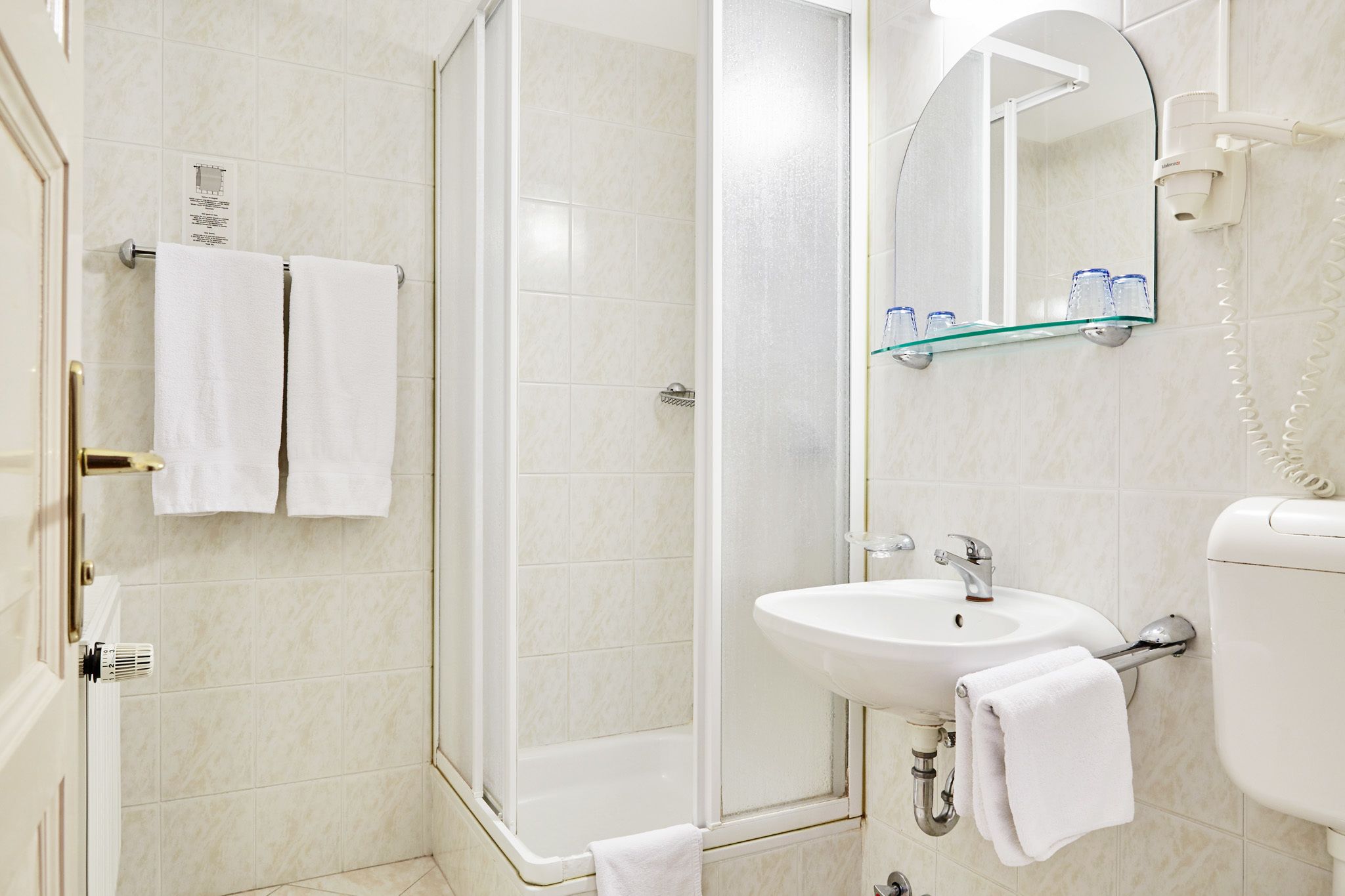 A bathroom with a glass-enclosed shower, a white sink, and a toilet.