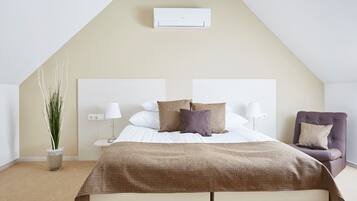 Een slaapkamer met een bed, bedlampen, een stoel, een potplant en een airconditioner.