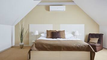 A bedroom with a bed, bedside lamps, a chair, a potted plant, and a ceiling fan.