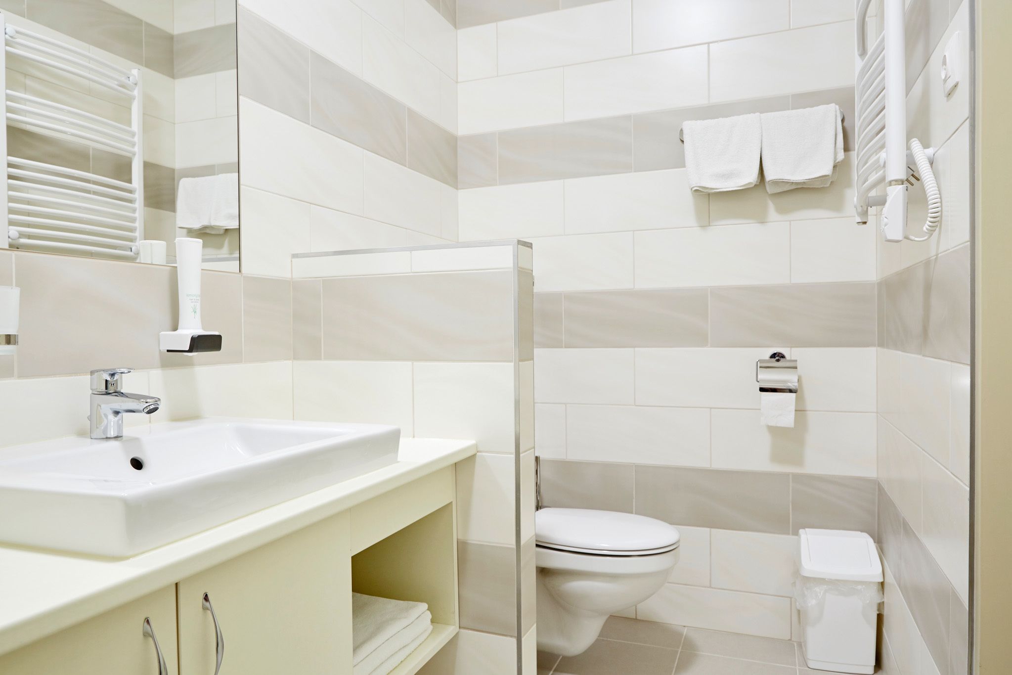 Une salle de bain moderne avec un lavabo, des toilettes et une zone de douche, le tout de couleur blanche.
