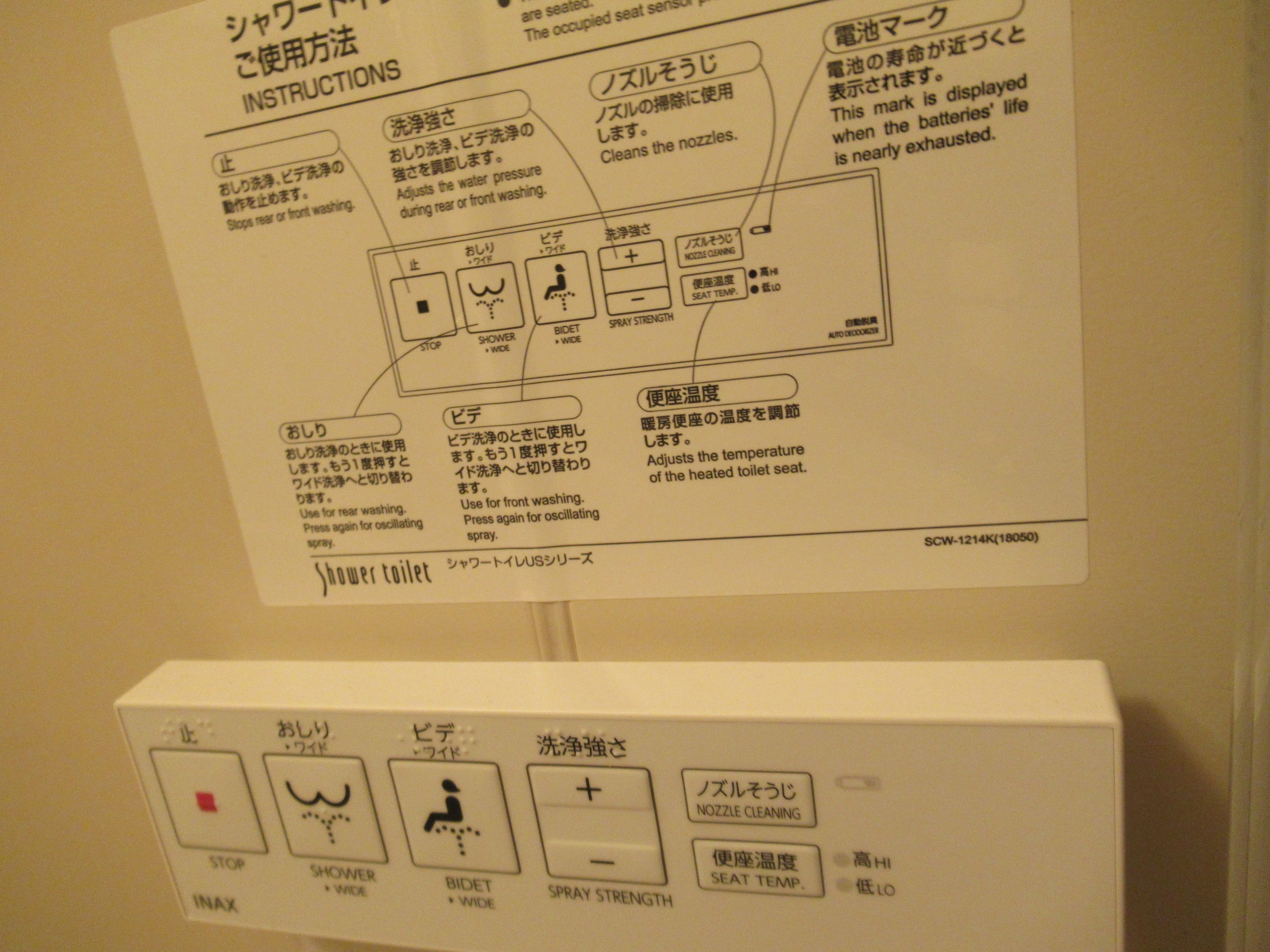 A control panel with Japanese instructions for a shower toilet, including buttons for stop, shower, bidet, nozzle cleaning, and seat temperature.