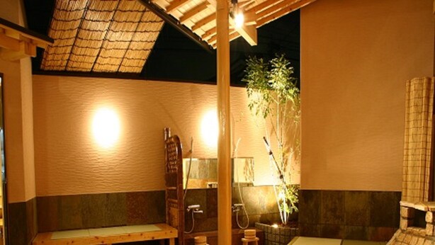 Un onsen japonés tradicional con bancos de madera y una zona de baño de piedra.
