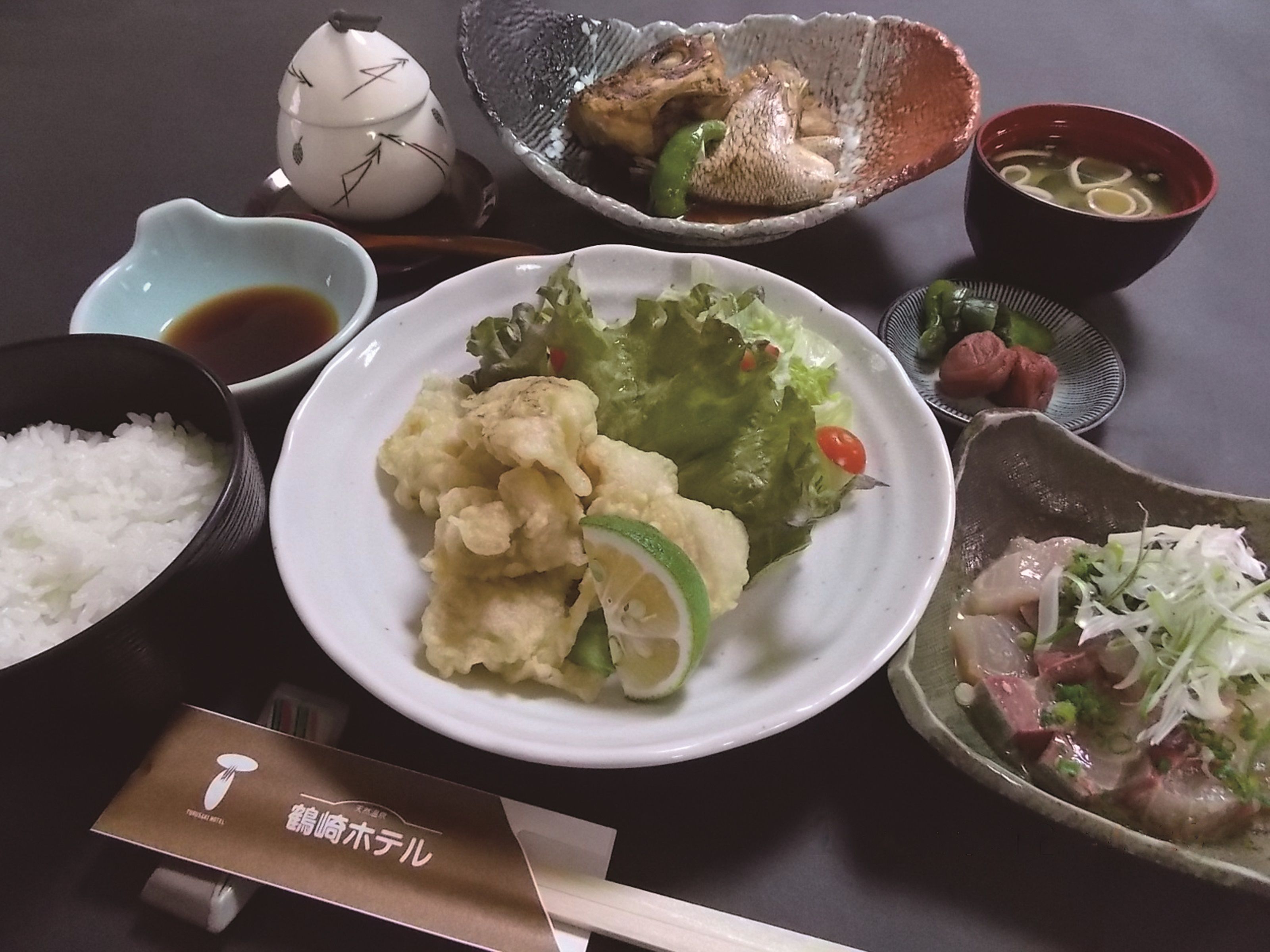 A table with various dishes including rice, tempura, and a bowl of soup.