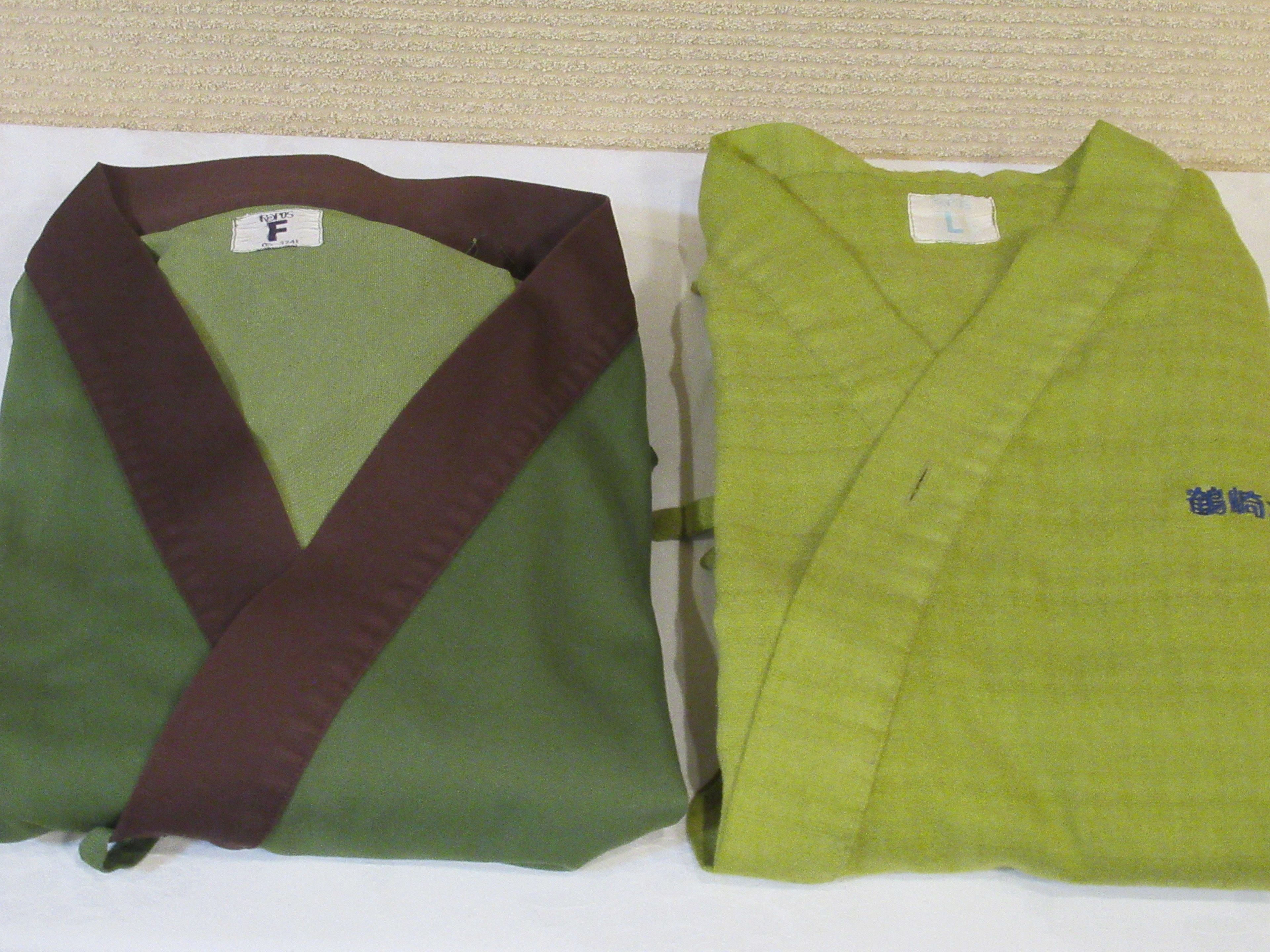 Dos prendas dobladas, una con un esquema de color verde y burdeos y la otra de color verde sólido, ambas sobre una superficie plana.