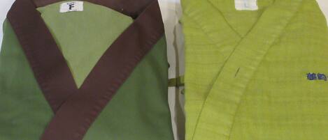 Dos prendas dobladas, una con un esquema de color verde y burdeos y la otra de color verde sólido, ambas sobre una superficie plana.