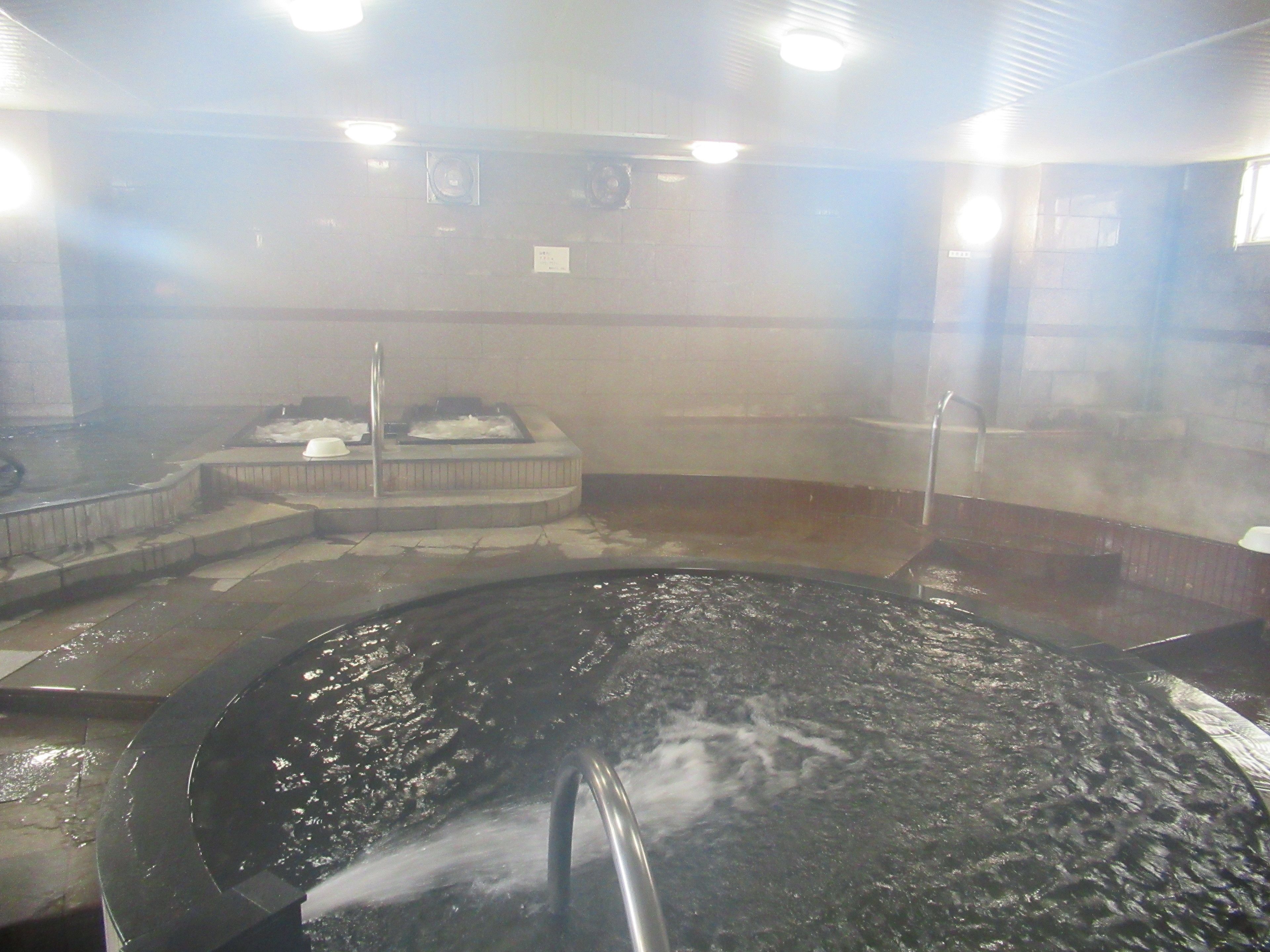 A hot spring bath with a circular stone basin and a steam vent.