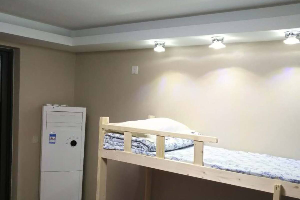 A bunk bed room with a ceiling light, a wall-mounted heater, and a door.