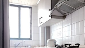 A modern kitchen with grey cabinets, a stainless steel range hood, and a window providing natural light. - Shanghai Yuelai Guest House - Hostel (Shanghai)