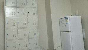 A room with a white metal locker storage unit and a white refrigerator. - Shanghai Yuelai Guest House - Hostel (Shanghai)
