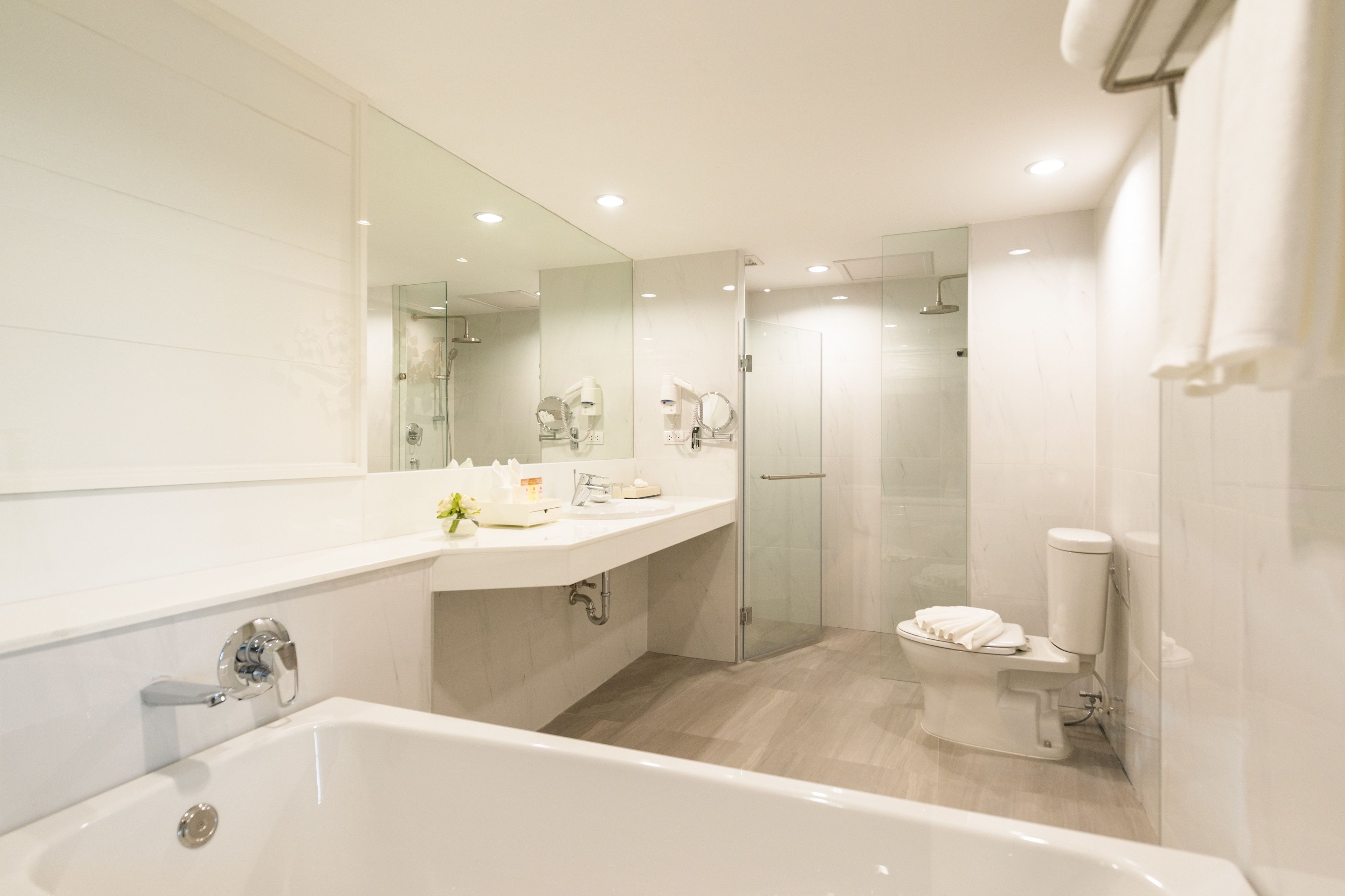 Un baño moderno con bañera, ducha con mampara de vidrio, inodoro y tocador con espejo.
