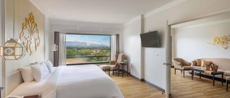 Habitación de hotel con una cama grande, un escritorio, una silla, un televisor y vistas al paisaje.