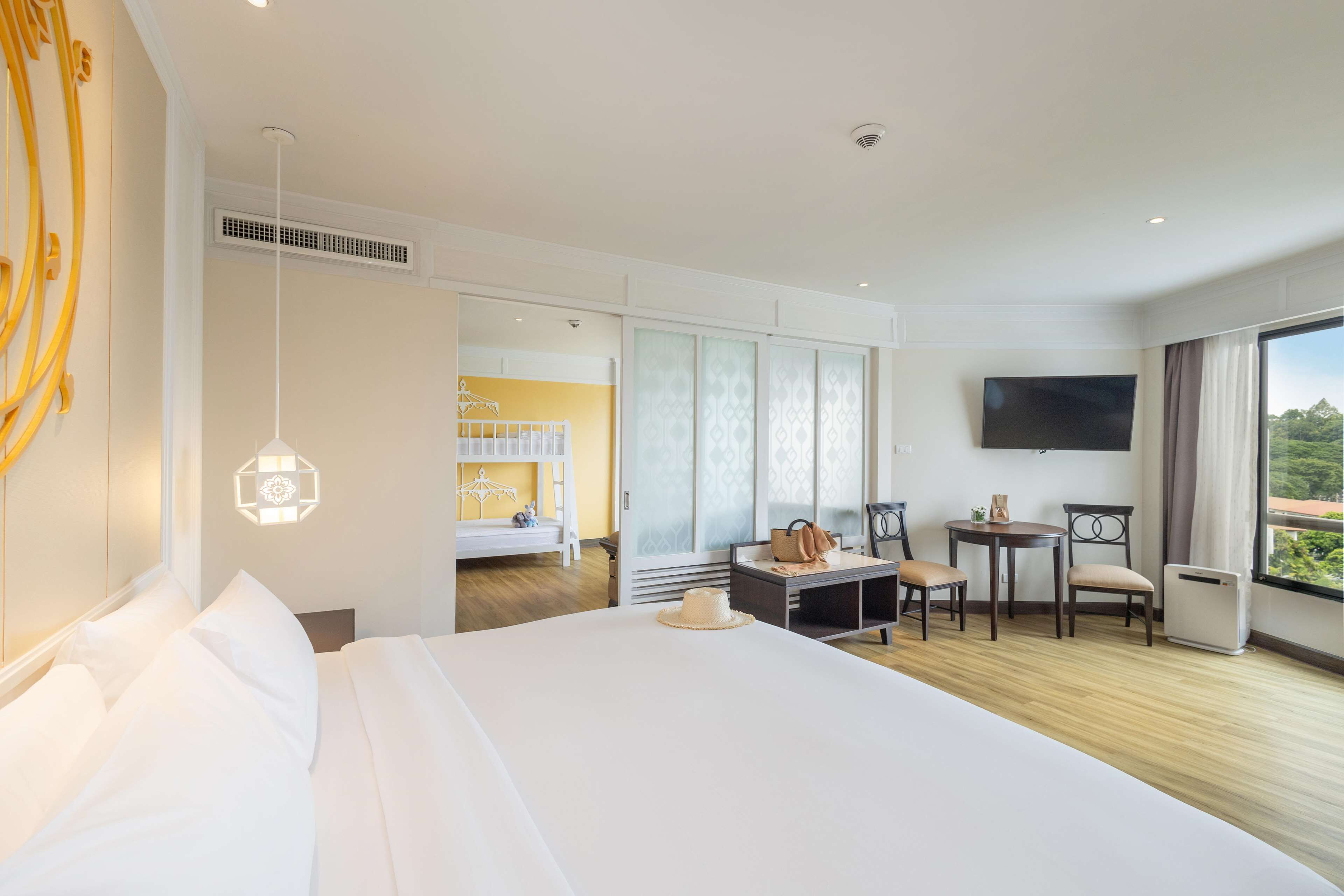 Une chambre d’hôtel avec un grand lit, un bureau avec des chaises, une télévision et une vue sur l’extérieur.