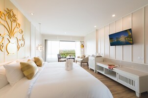 Una habitación de hotel moderna con una cama grande, televisión, zona de estar y vistas al exterior.