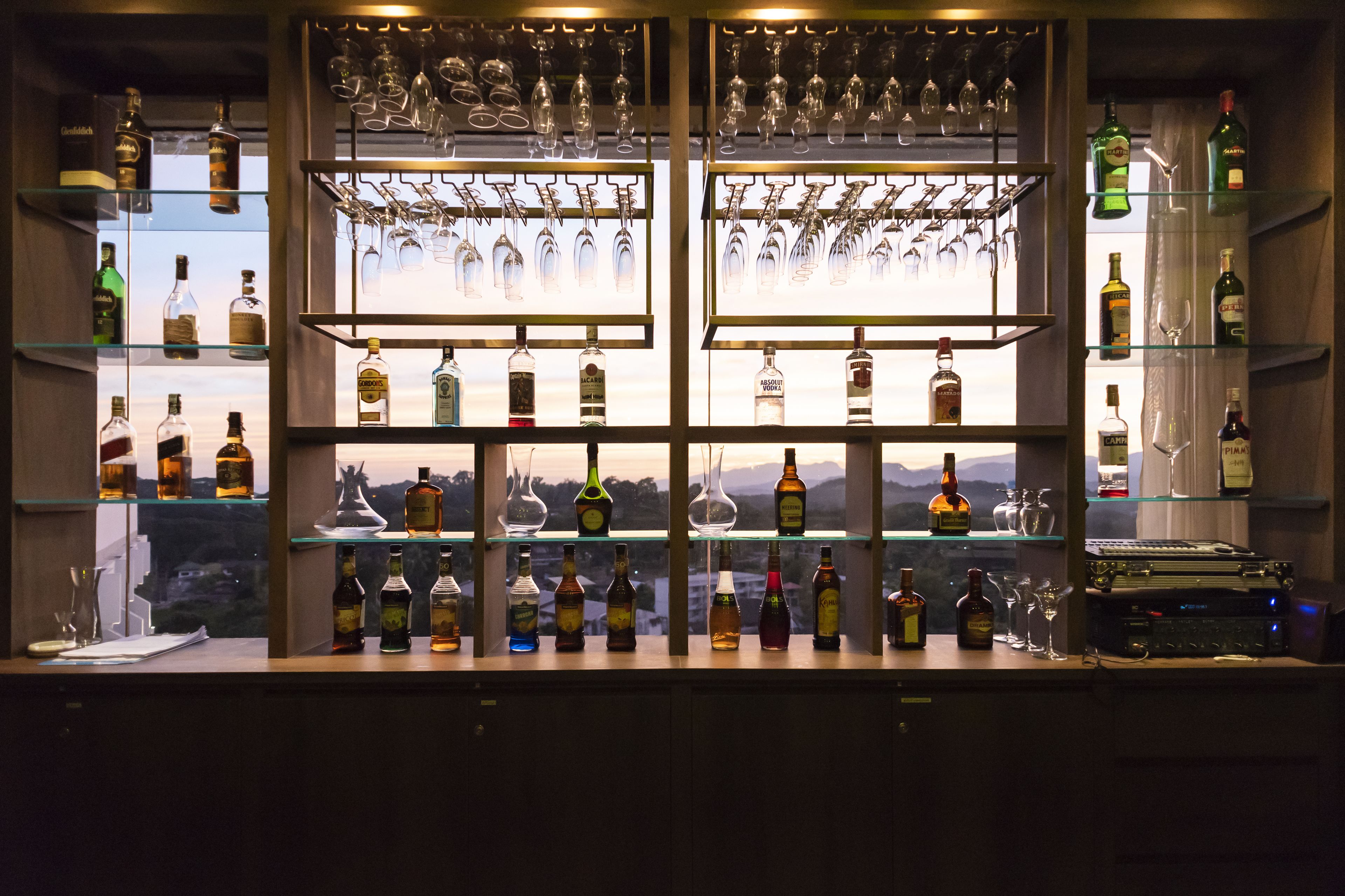 Un espace bar avec des étagères remplies de bouteilles d  ’alcool et de verres à vin.