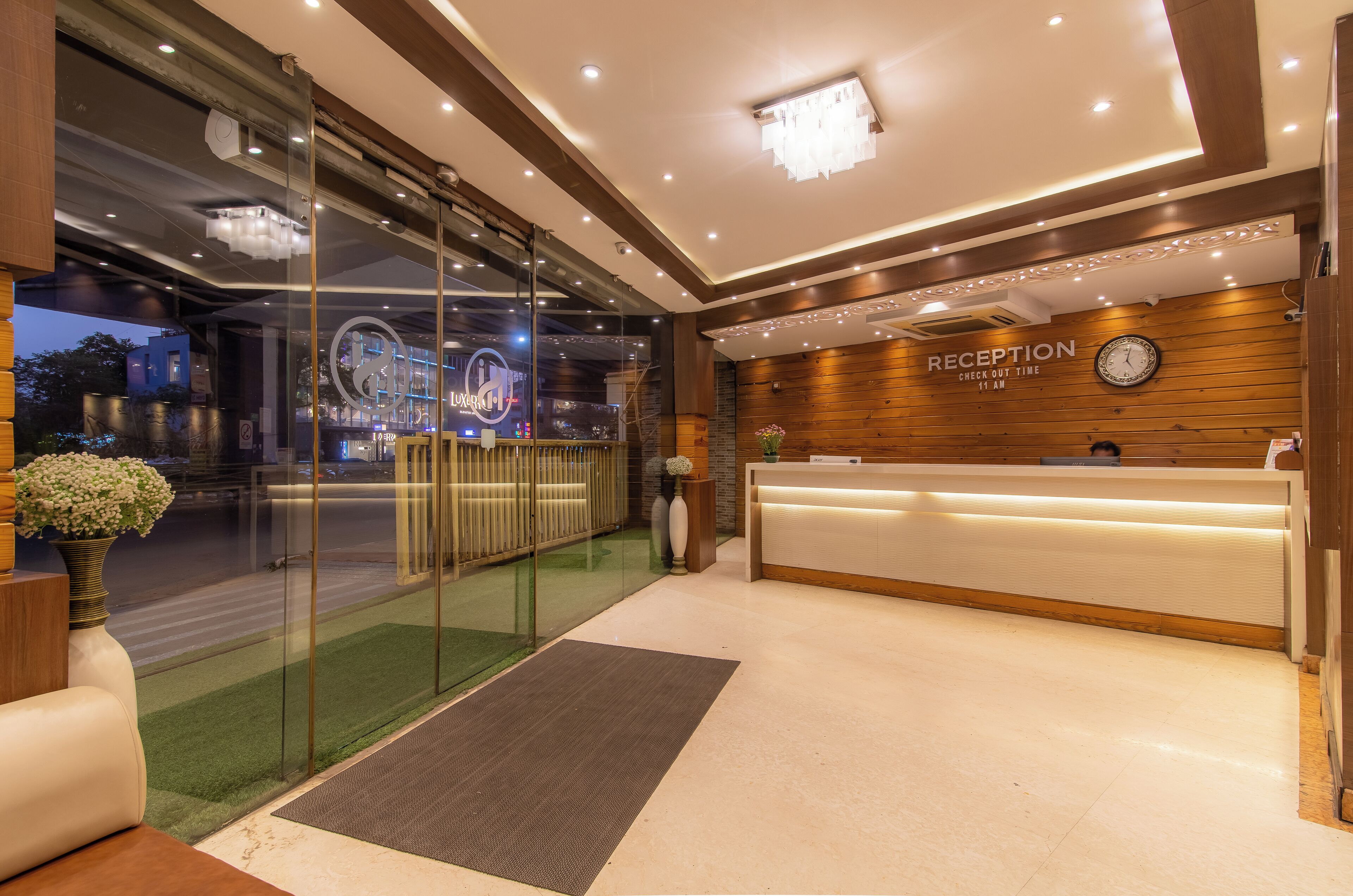 Zona de recepción de un hotel con mostrador, un reloj y un cartel con la hora de salida.